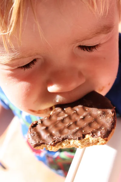 Child eating chocolate biscuit — Stock Photo, Image