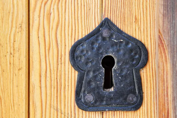 Oude zwarte sleutelgat op houten deur Stockfoto