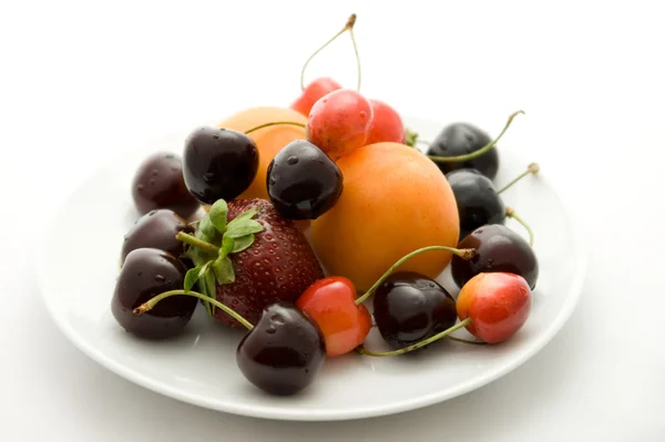 Apricots, strawberry and cherries on the plate — Stock Photo, Image