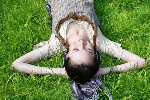 Jonge vrouw liggen op het gras — Stockfoto