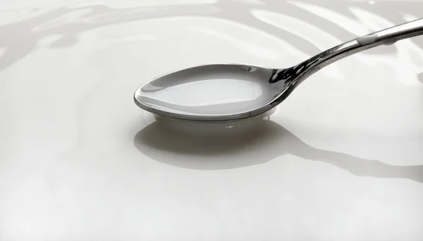 Stock image Spoon full of milk over a bowl