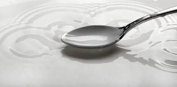 stock image Spoon full of milk over a bowl