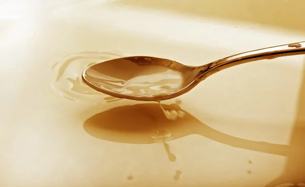 Stock image Spoon full of milk over a bowl