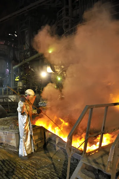 Разливка расплавленной горячей стали и рабочий — стоковое фото