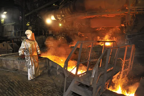 Разливка расплавленной горячей стали и рабочий — стоковое фото