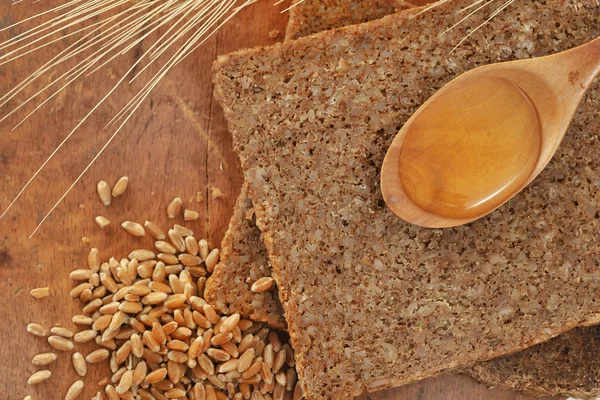 Pão integral fatiado e colher de mel — Fotografia de Stock