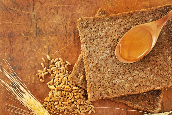 Нарізаний цілісний хліб і медова ложка — стокове фото