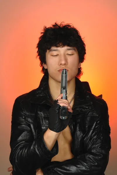 Azjatycki człowiek z zamkniętymi oczami, trzymając pistolet — Zdjęcie stockowe