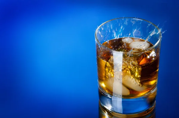 Whisky splash on a blue bg — Stock Photo, Image