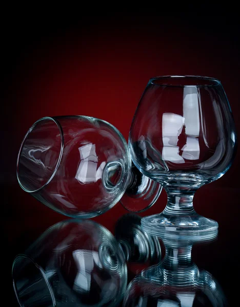 Två cognac glas på en röd bg — Stockfoto