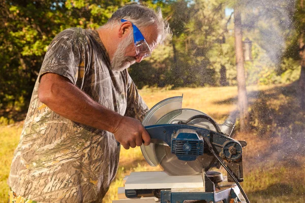 Hombre mayor operando una sierra picadora — Foto de Stock