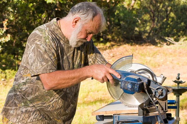 Hombre mayor cortando madera — Foto de Stock