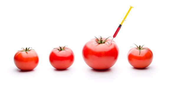 Syringe injecteren rode vloeistof in een groene tomaat — Stockfoto
