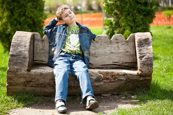 Симпатичный ребенок сидит на скамейке запасных — стоковое фото