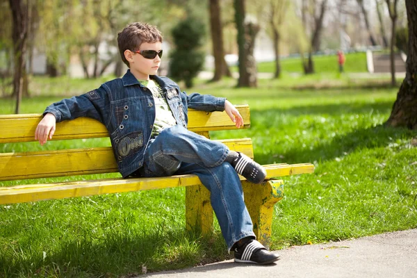 Fajny dzieciak siedzi na ławce — Zdjęcie stockowe