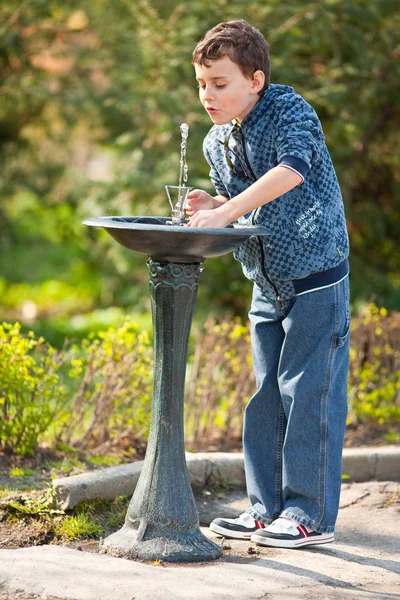 Милый ребенок пьет воду в парке — стоковое фото
