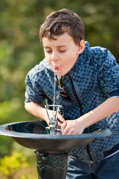 Lindo niño bebiendo agua en un parque — Foto de Stock
