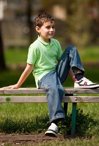 Netter kleiner Junge sitzt auf einer Bank — Stockfoto