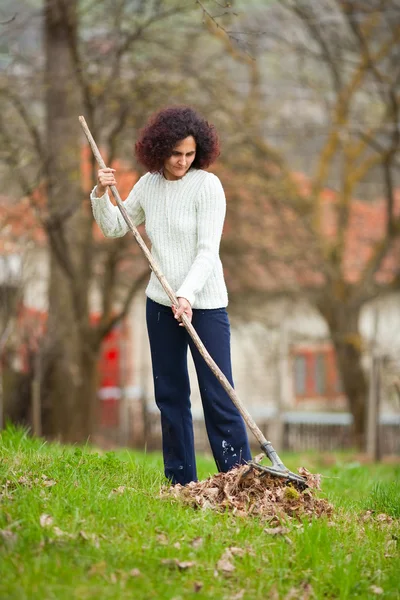 Redhead woman using a rake for cleaning — Zdjęcie stockowe