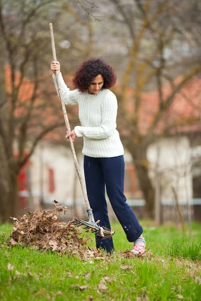 Redhead woman using a rake for cleaning — Zdjęcie stockowe