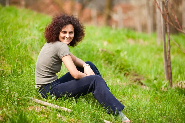 Rödhårig dam som sitter i gräset — Stockfoto