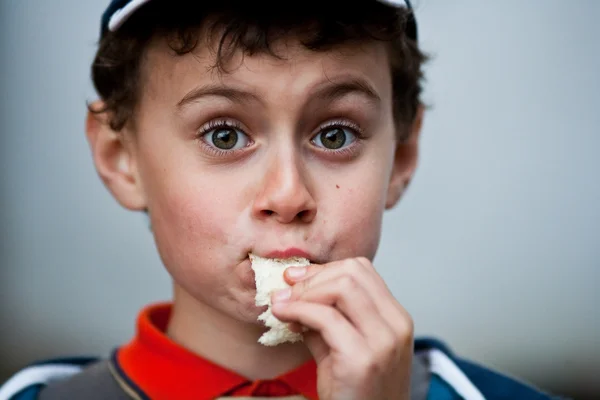 Смешной маленький мальчик ест хлеб — стоковое фото