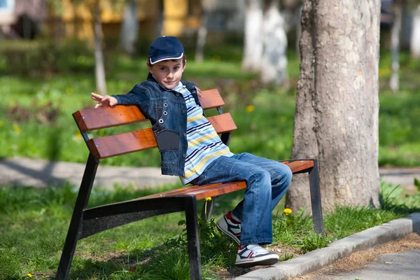 Kid op een bankje buitenshuis — Stockfoto