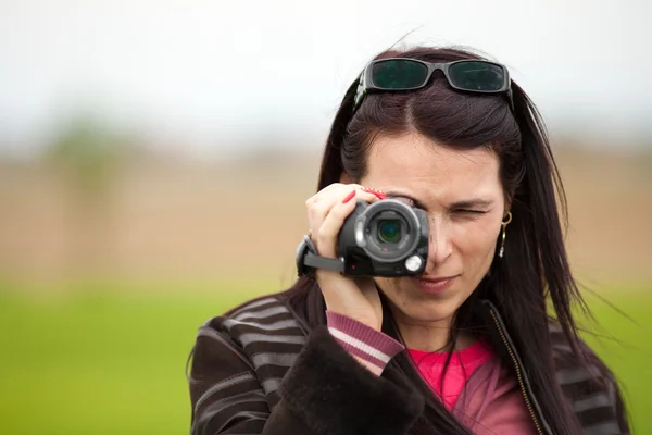 Jeune femme utilisant une caméra vidéo en plein air — Photo
