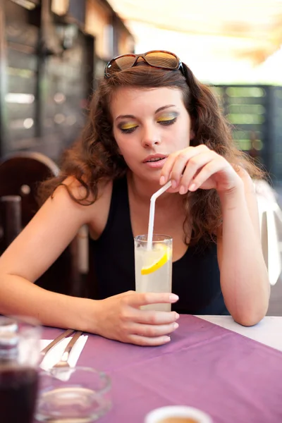 Mujer joven bebiendo refresco en un restaurante — Foto de Stock