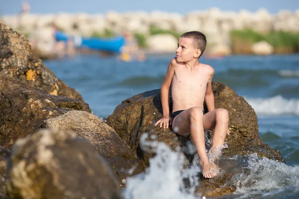Niño sentado en las rocas en el mar —  Fotos de Stock