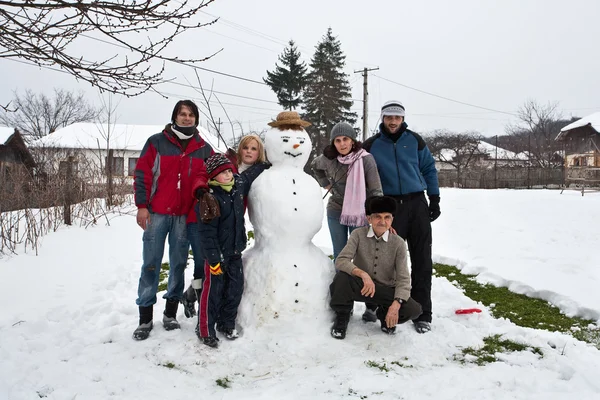Šťastná rodina kolem sněhulák — Stock fotografie