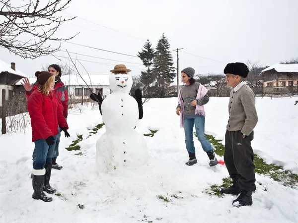 Šťastná rodina kolem sněhulák — Stock fotografie