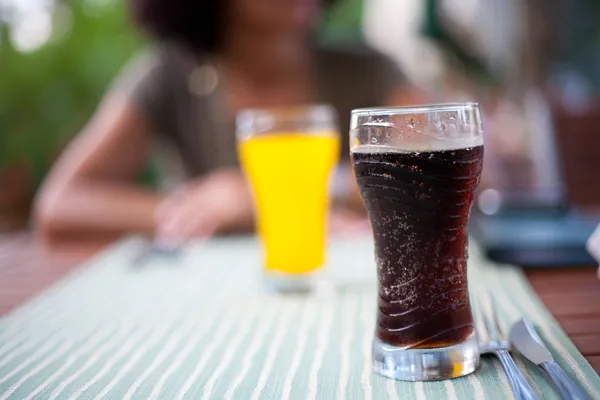 Glas med Cola och dam i bakgrunden — Stockfoto