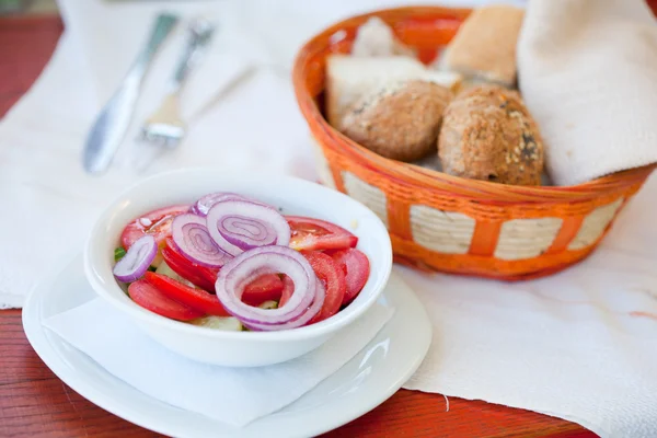 バック グラウンドでパンとトマトと玉ねぎのサラダ — ストック写真
