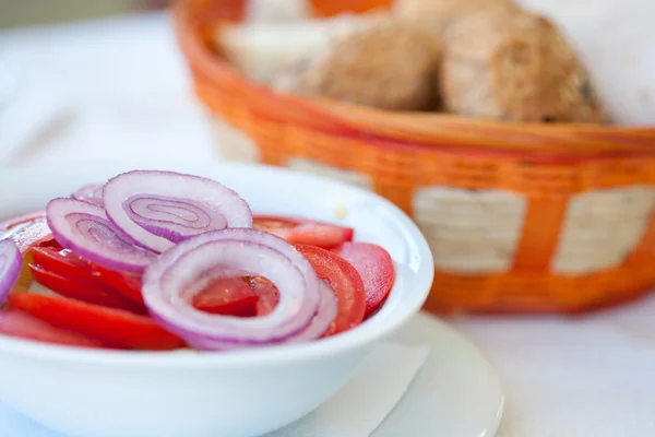 Tomato and onions salad with bread in background — Stock Photo, Image