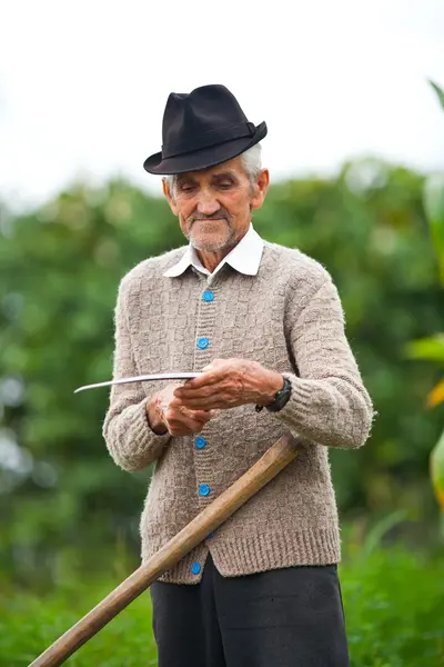 Старик, использующий косу — стоковое фото
