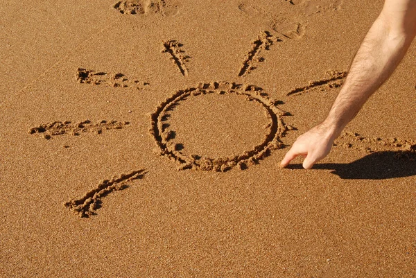 Hand drawing a sun in the sand — Stock Photo, Image