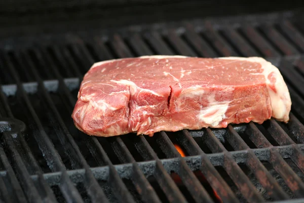 Raw steak on a BBQ grill — Stock Photo, Image