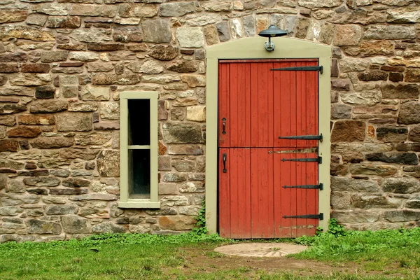 Red door on a old stone building — Stock Photo, Image