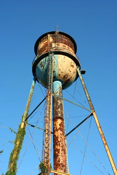 Vecchia torre d'acqua arrugginita contro il cielo blu — Foto Stock
