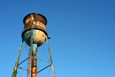 Old rusty watertower against blue sky clipart