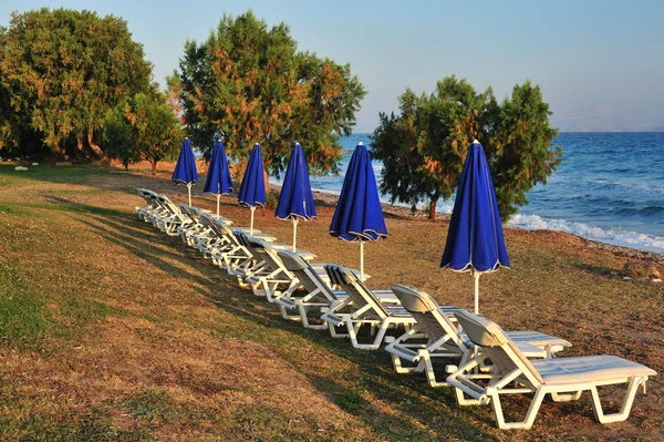 Spiaggia con ombrelloni blu ripiegati — Foto Stock
