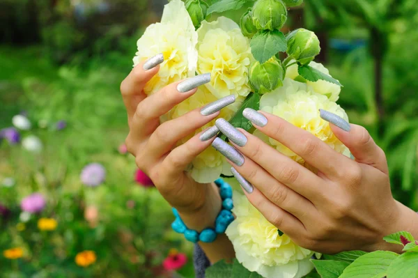 Manicure on real nails and yellow hollyhock flower — Stock Photo, Image