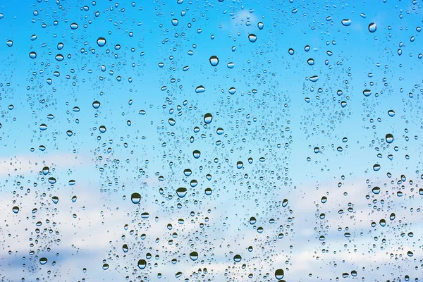 Капли воды на стекле против голубого неба — стоковое фото