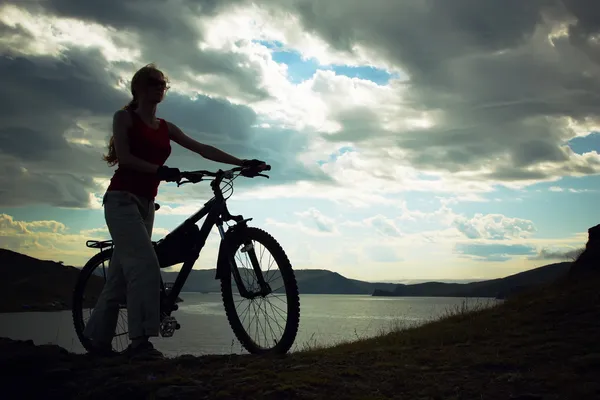 山に対して自転車を持つ少女のシルエット — Stock fotografie