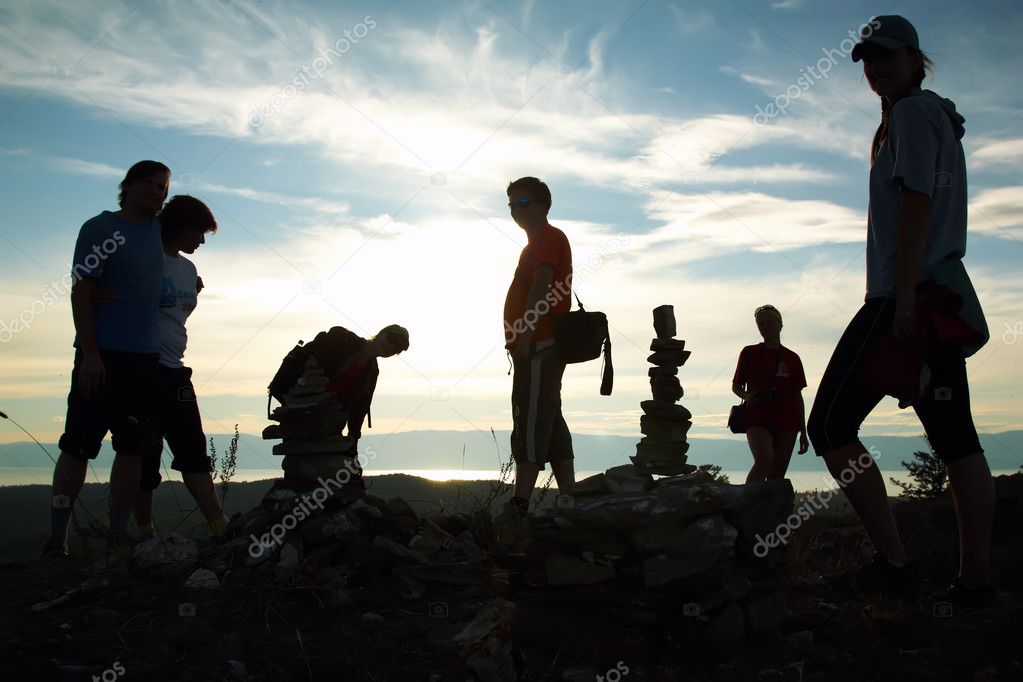 Silhouette of group of at top of mountain against a decline