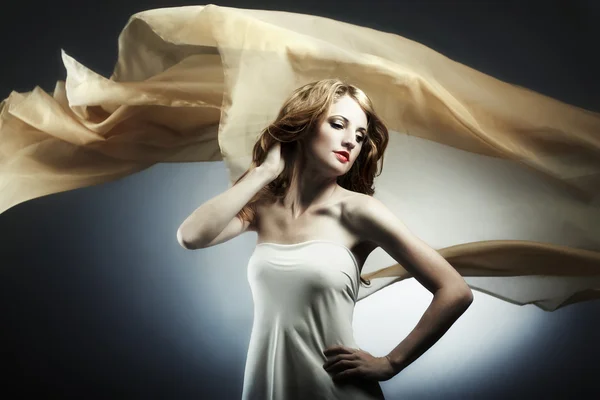 Портрет молодой женщины на фоне летающей ткани — стоковое фото