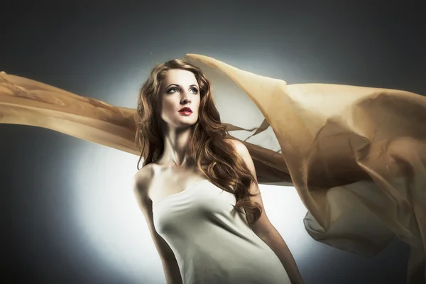 Retrato da jovem mulher contra um tecido voador — Fotografia de Stock