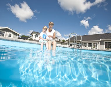 Mother and daughter at the swiiming pool clipart