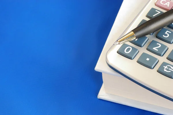 Ручка и калькулятор на книге — стоковое фото
